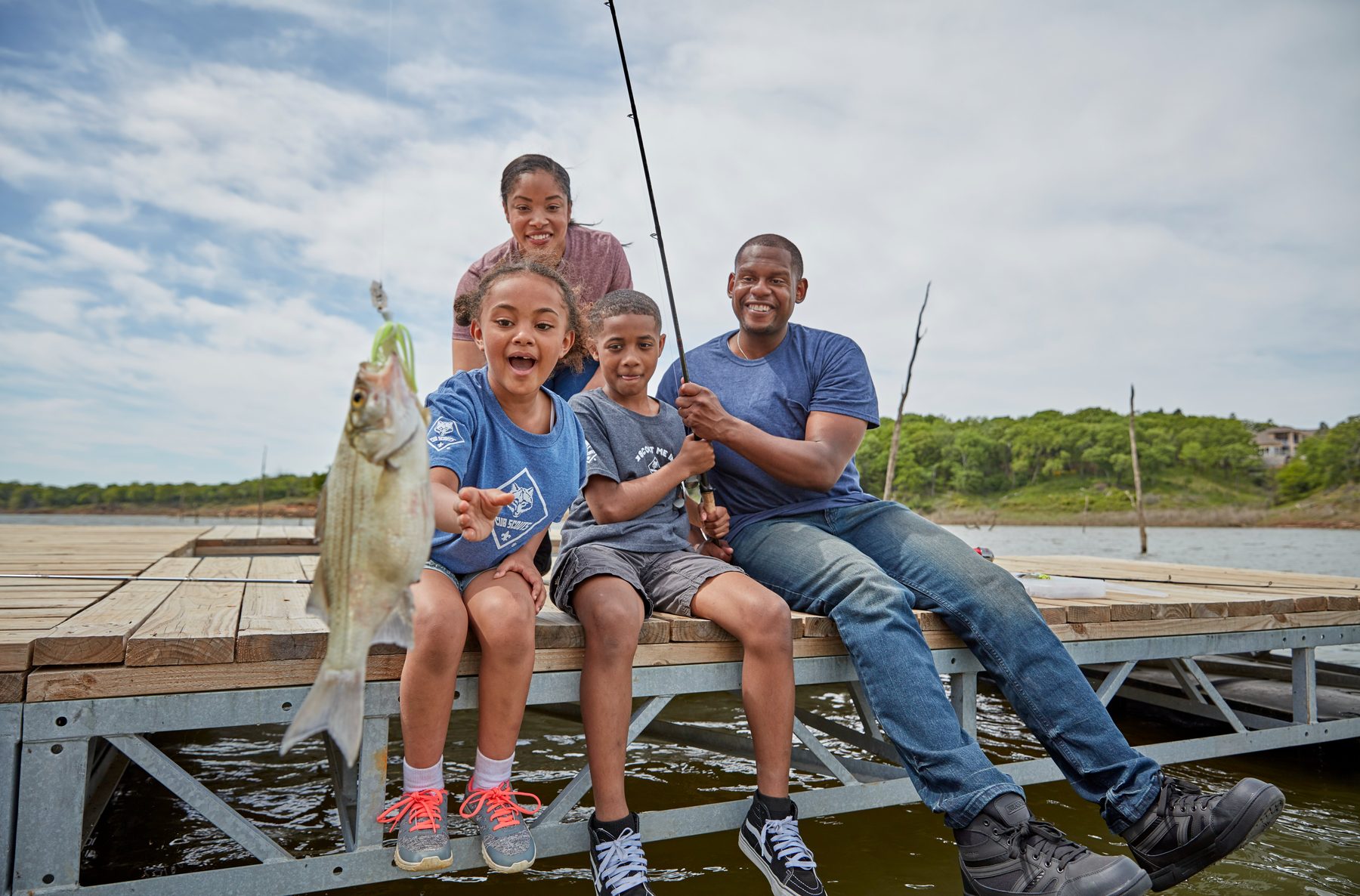 A scout family fishing together off a dock