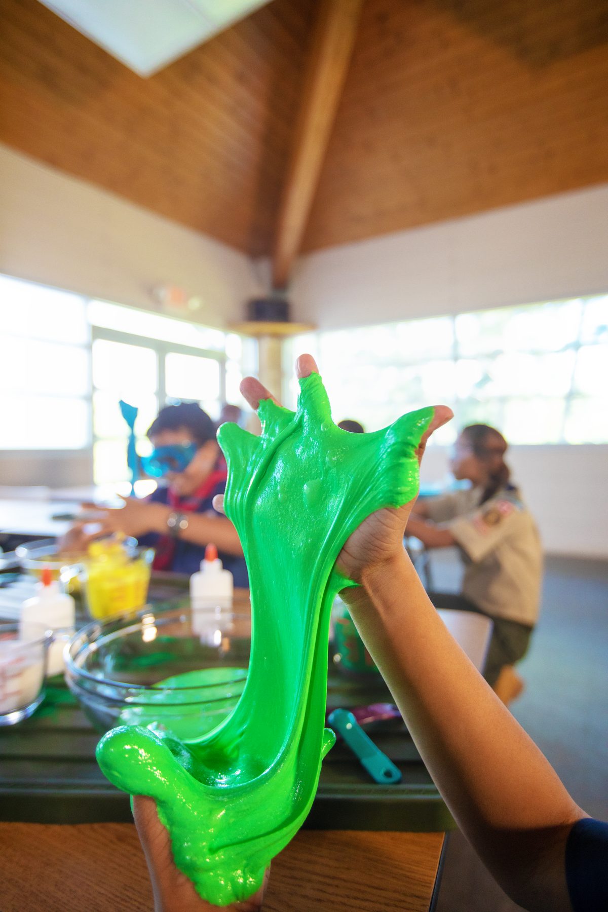 A scout holding up homemade green slime at a den meeting